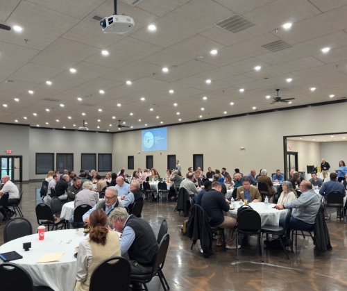 wide angle of large conference room with round tables and dozens of attendees